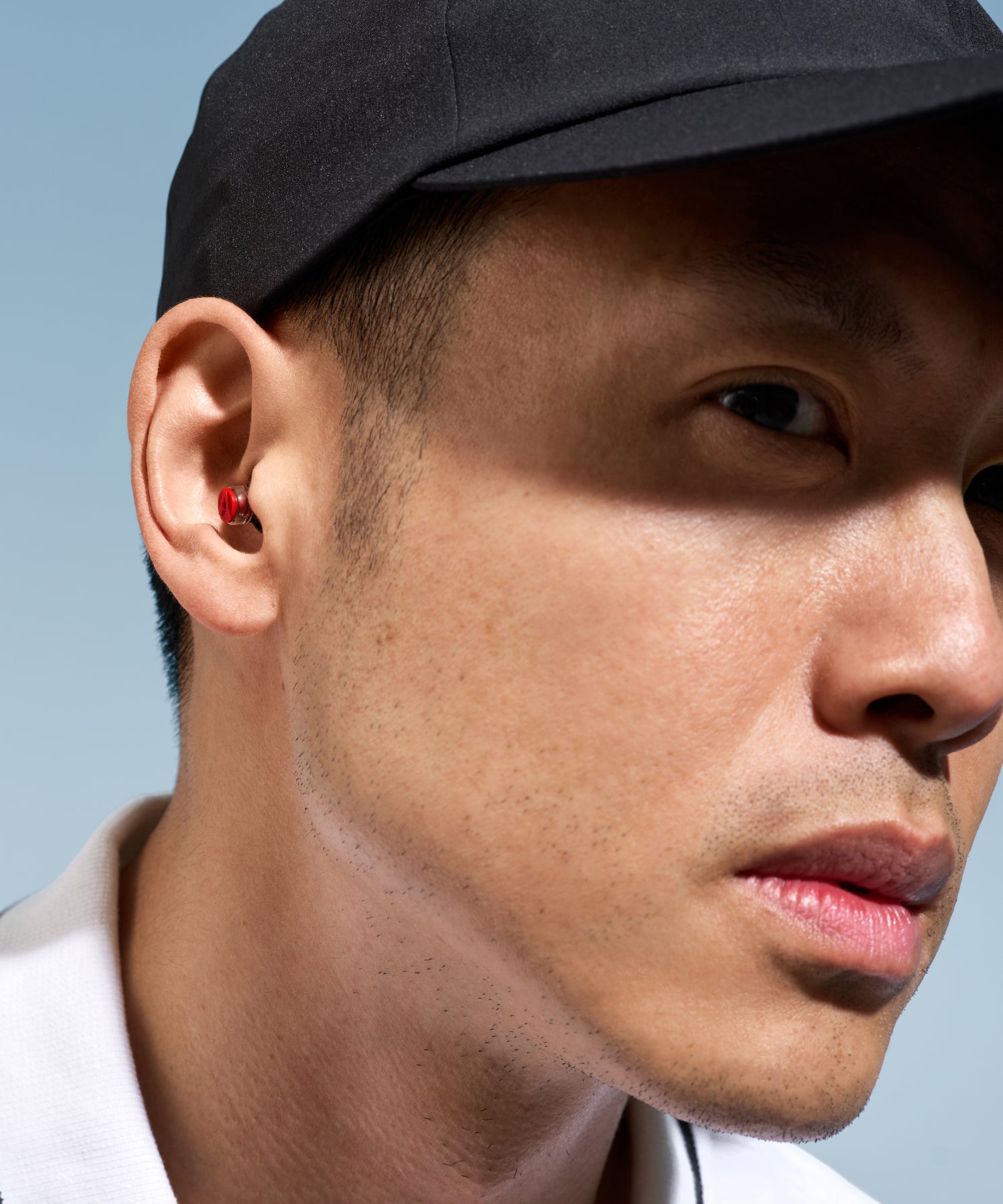 Alpine Formula 1® earplug worn in the ear by a man in a black cap 